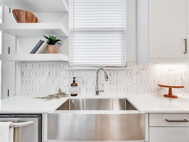 kitchen featuring backsplash, white cabinetry, stainless steel dishwasher, and sink