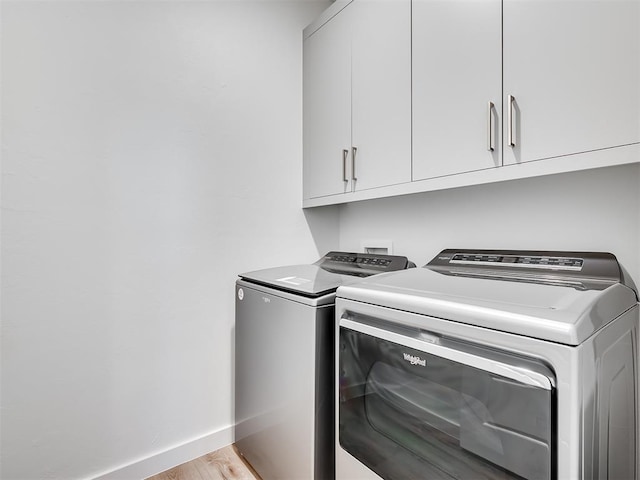 laundry area featuring cabinets, light hardwood / wood-style floors, and washing machine and clothes dryer