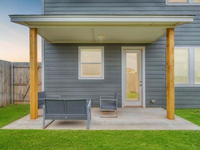 exterior entry at dusk featuring a yard, outdoor lounge area, and a patio