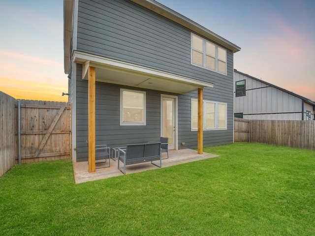 back house at dusk with a yard and a patio