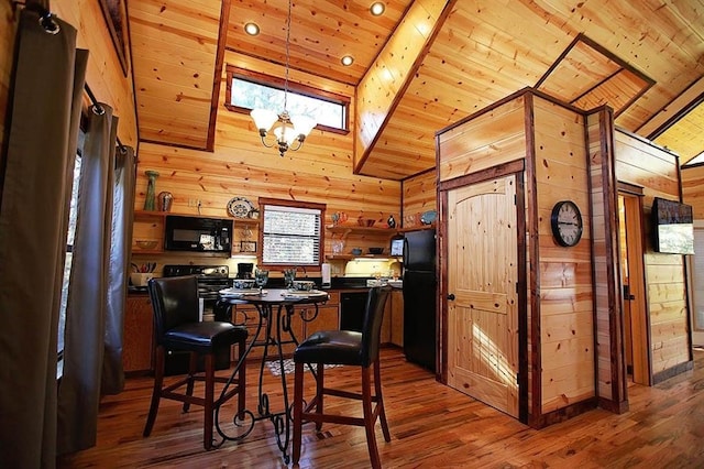 kitchen with wooden ceiling, black appliances, wooden walls, hardwood / wood-style flooring, and a kitchen bar