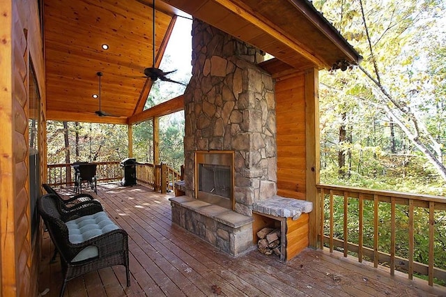 wooden deck with an outdoor stone fireplace and ceiling fan