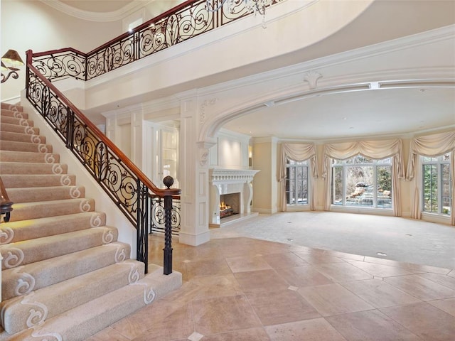 foyer with ornate columns, carpet floors, a high ceiling, and ornamental molding