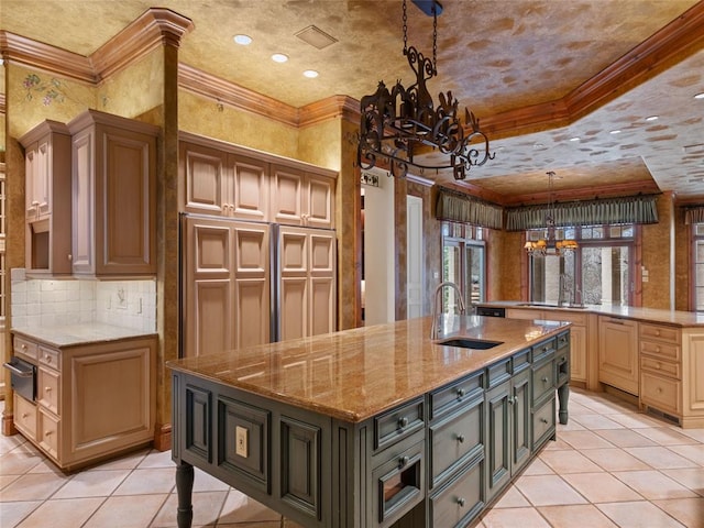 kitchen with light stone countertops, sink, a notable chandelier, decorative light fixtures, and a kitchen island with sink