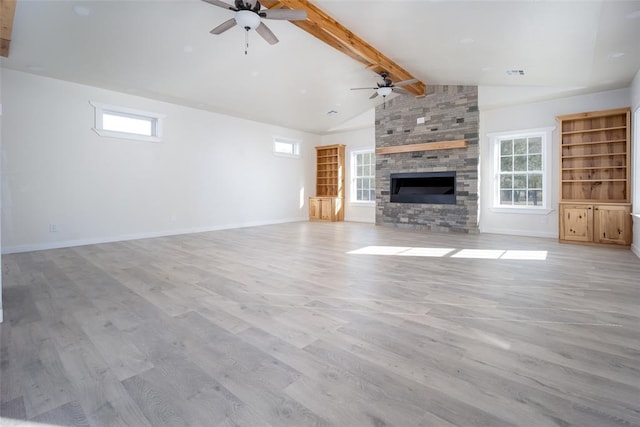 unfurnished living room featuring vaulted ceiling with beams, ceiling fan, a stone fireplace, and light wood-type flooring