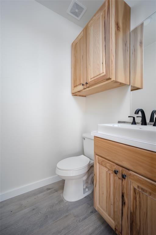 bathroom with vanity, toilet, and wood-type flooring