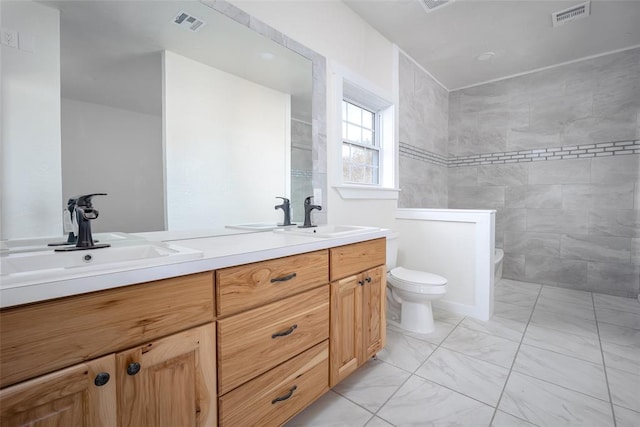 bathroom with tiled shower, vanity, and toilet