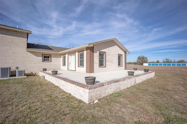 back of property with a lawn, a patio area, and central air condition unit