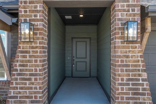 view of exterior entry featuring brick siding