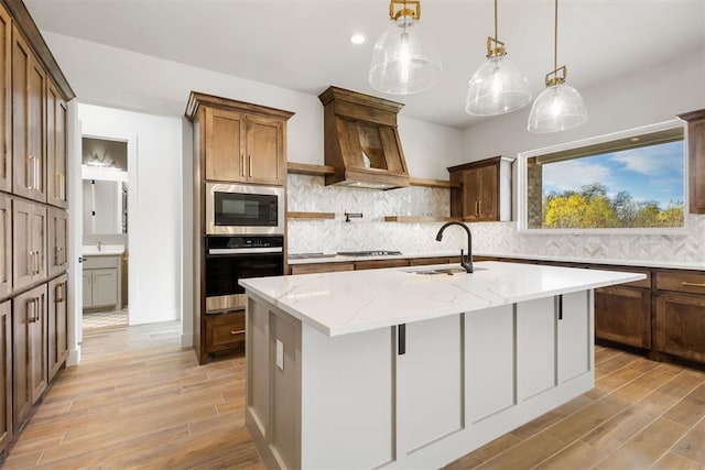 kitchen with pendant lighting, a kitchen island with sink, light stone countertops, a breakfast bar area, and stainless steel appliances