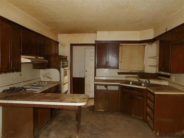 kitchen featuring kitchen peninsula, sink, concrete flooring, and a textured ceiling