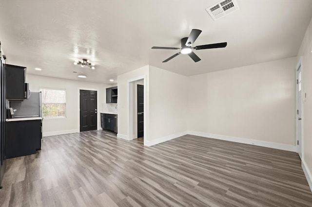 unfurnished living room featuring ceiling fan and dark wood-type flooring