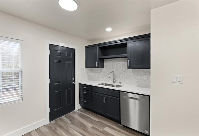 kitchen with backsplash, sink, stainless steel dishwasher, and light hardwood / wood-style floors