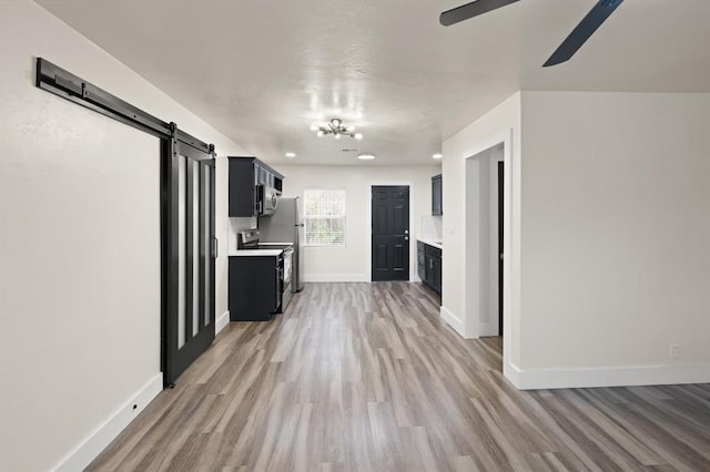 unfurnished living room featuring ceiling fan, a barn door, and light wood-type flooring