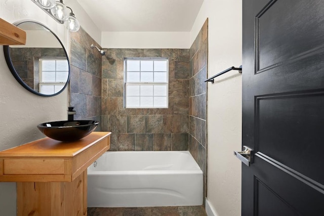 bathroom featuring vanity and tiled shower / bath