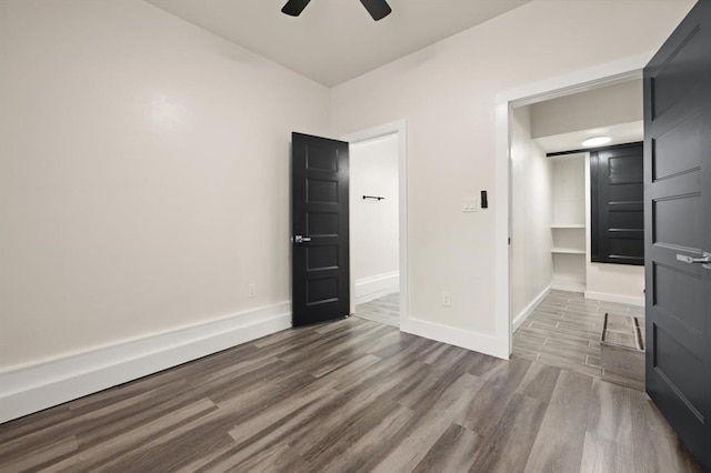 unfurnished bedroom with hardwood / wood-style flooring, ceiling fan, a walk in closet, and a closet