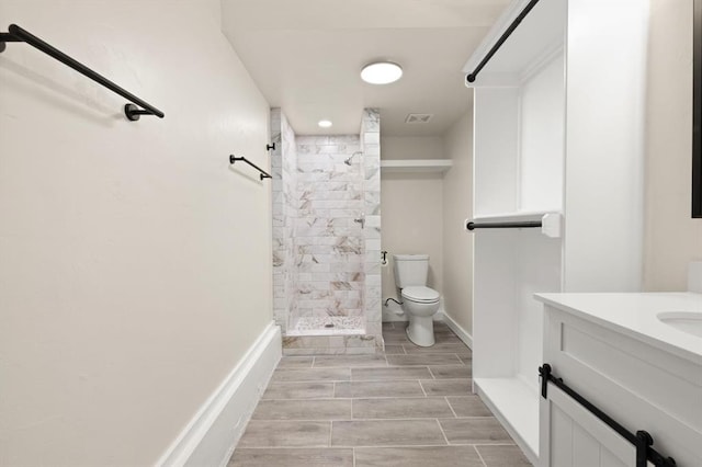 bathroom with vanity, toilet, and tiled shower