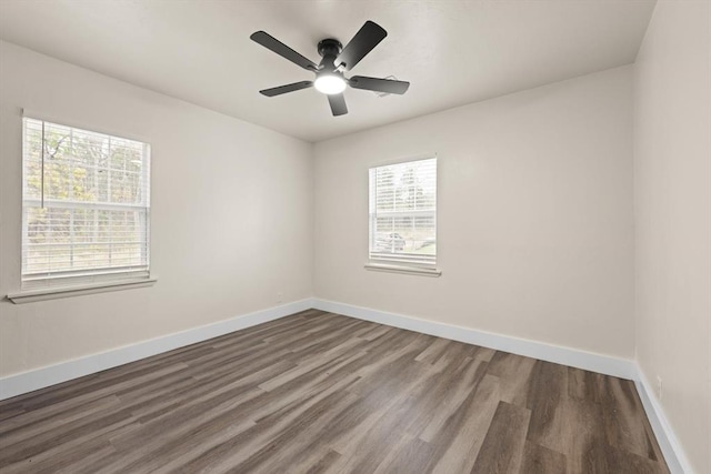 spare room featuring ceiling fan, a healthy amount of sunlight, and dark hardwood / wood-style flooring