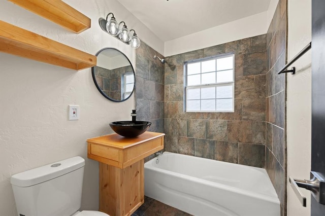 full bathroom featuring vanity, tiled shower / bath combo, and toilet