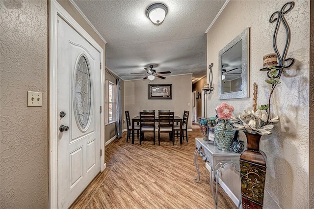 entryway with ceiling fan, light hardwood / wood-style floors, crown molding, and a textured ceiling