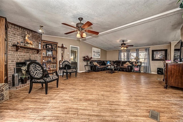 living room with ceiling fan, light hardwood / wood-style floors, a textured ceiling, and vaulted ceiling