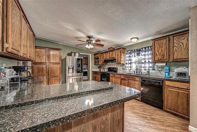 kitchen featuring kitchen peninsula, black appliances, a textured ceiling, and light hardwood / wood-style floors