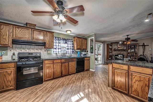 kitchen with a textured ceiling, light hardwood / wood-style floors, a brick fireplace, and black appliances