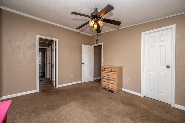 unfurnished bedroom featuring ensuite bath, ceiling fan, dark colored carpet, a textured ceiling, and ornamental molding