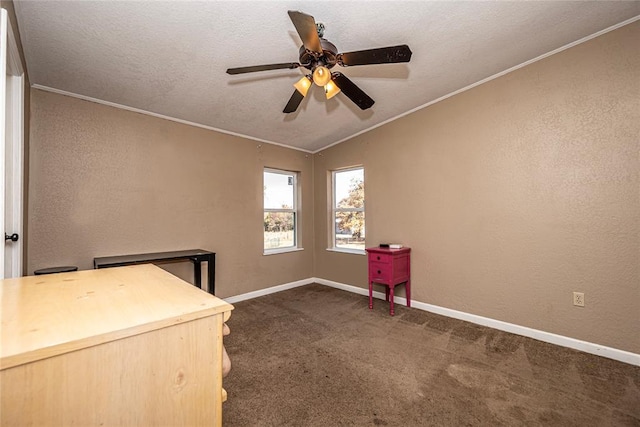 unfurnished office with dark colored carpet, vaulted ceiling, ceiling fan, ornamental molding, and a textured ceiling