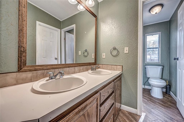 bathroom with hardwood / wood-style floors, vanity, ornamental molding, and toilet