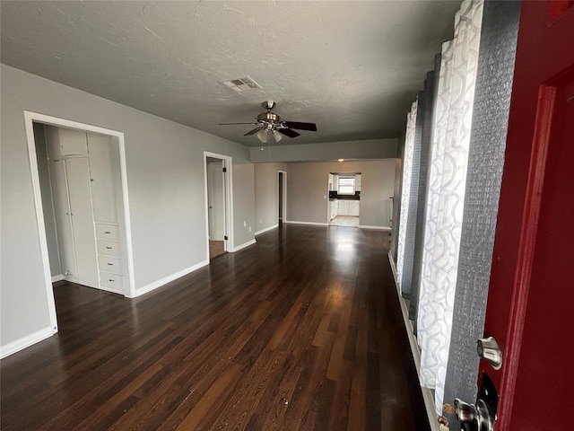 unfurnished living room with ceiling fan and dark wood-type flooring