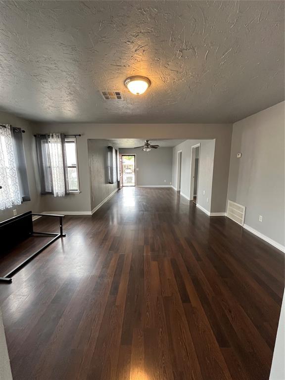 empty room featuring a textured ceiling, dark hardwood / wood-style floors, and ceiling fan