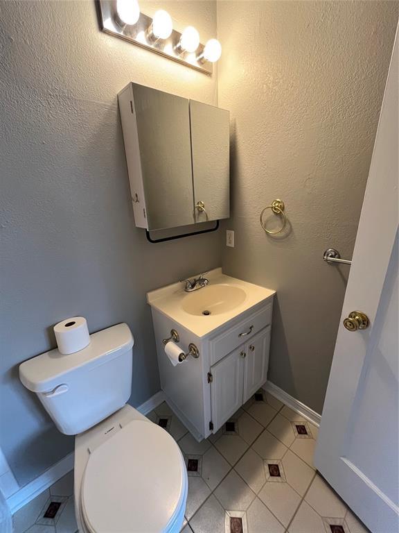 bathroom with toilet, vanity, and tile patterned floors