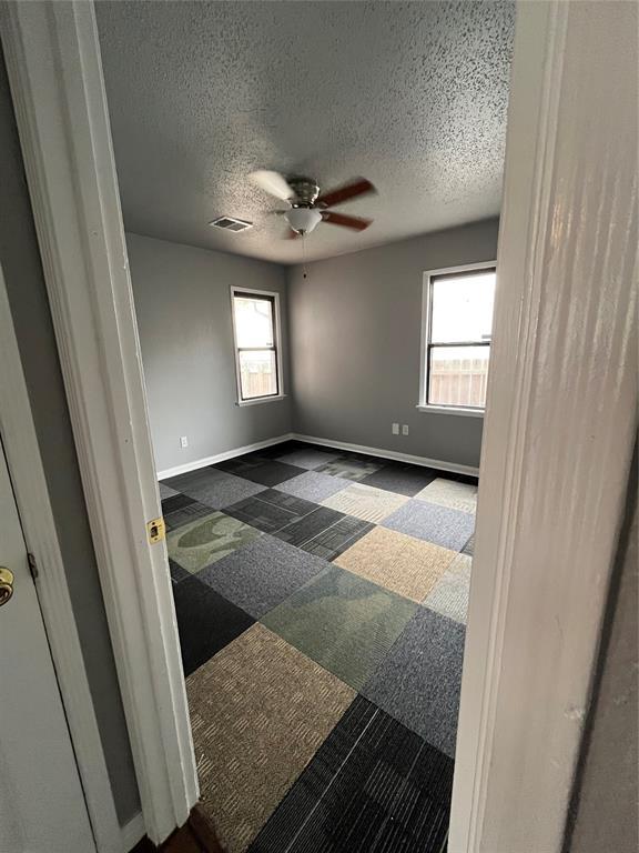 spare room with a wealth of natural light, ceiling fan, and a textured ceiling