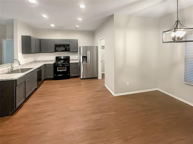 kitchen featuring sink, an inviting chandelier, light hardwood / wood-style flooring, decorative light fixtures, and black appliances