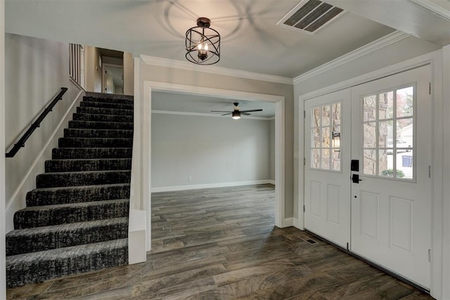 foyer entrance with ceiling fan with notable chandelier, ornamental molding, and dark wood-type flooring