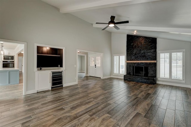 unfurnished living room with a stone fireplace, ceiling fan, beverage cooler, and dark hardwood / wood-style floors