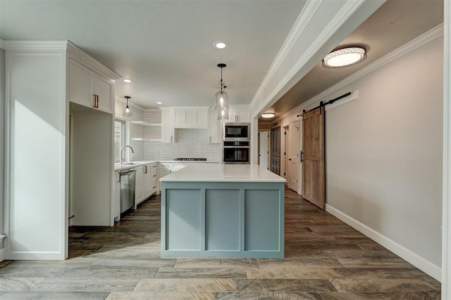 kitchen with a center island, white cabinets, light hardwood / wood-style flooring, a barn door, and appliances with stainless steel finishes