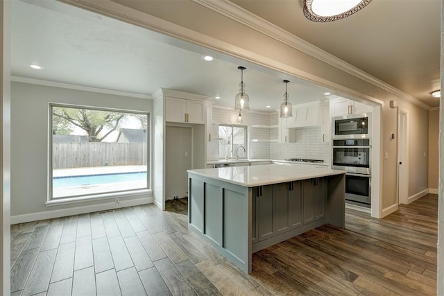 kitchen featuring tasteful backsplash, a kitchen island, pendant lighting, light hardwood / wood-style floors, and white cabinetry