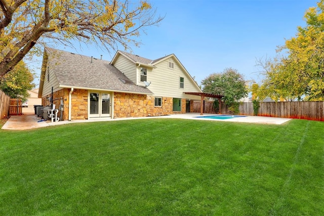 rear view of property featuring french doors, a yard, a fenced in pool, and a patio area