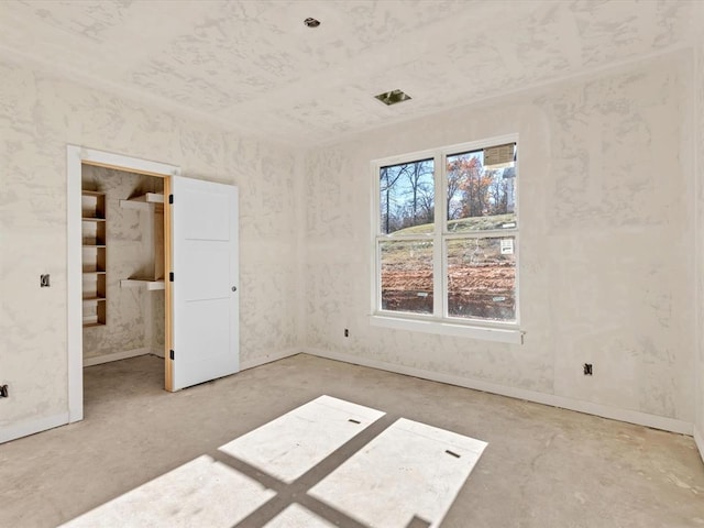 unfurnished bedroom with concrete flooring and a spacious closet