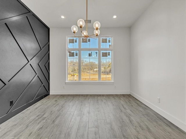 unfurnished dining area with recessed lighting, a chandelier, baseboards, and wood finished floors