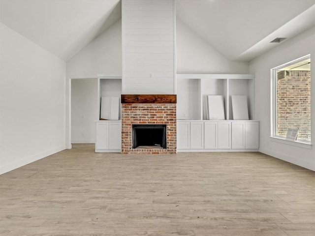 unfurnished living room featuring a brick fireplace, visible vents, high vaulted ceiling, and light wood-type flooring