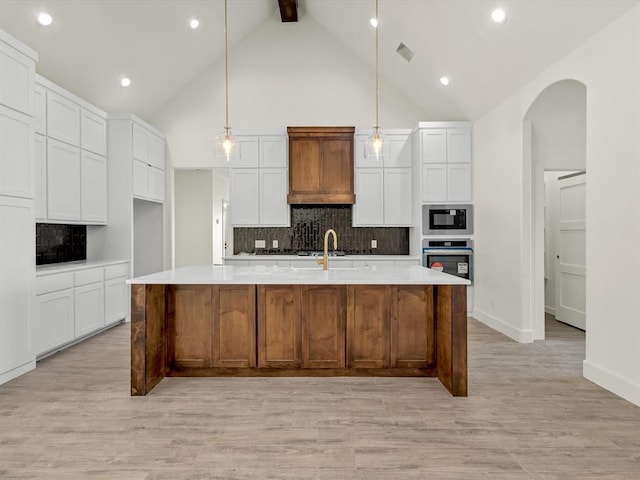 kitchen with oven, built in microwave, arched walkways, and decorative backsplash