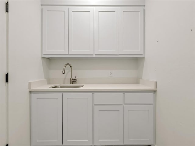 kitchen featuring white cabinetry, light countertops, and a sink