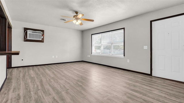 unfurnished living room featuring ceiling fan, light hardwood / wood-style floors, and an AC wall unit