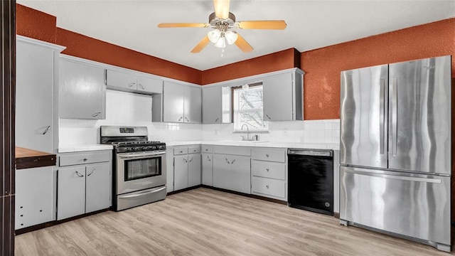 kitchen with gray cabinetry, ceiling fan, sink, stainless steel appliances, and light hardwood / wood-style floors