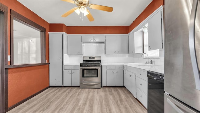 kitchen with decorative backsplash, appliances with stainless steel finishes, ceiling fan, sink, and light hardwood / wood-style floors