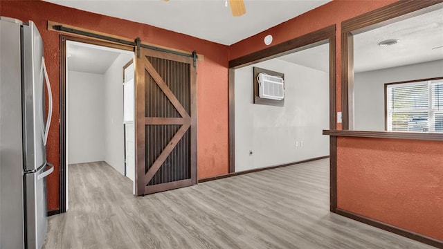 corridor featuring a wall mounted air conditioner, a barn door, and light hardwood / wood-style flooring