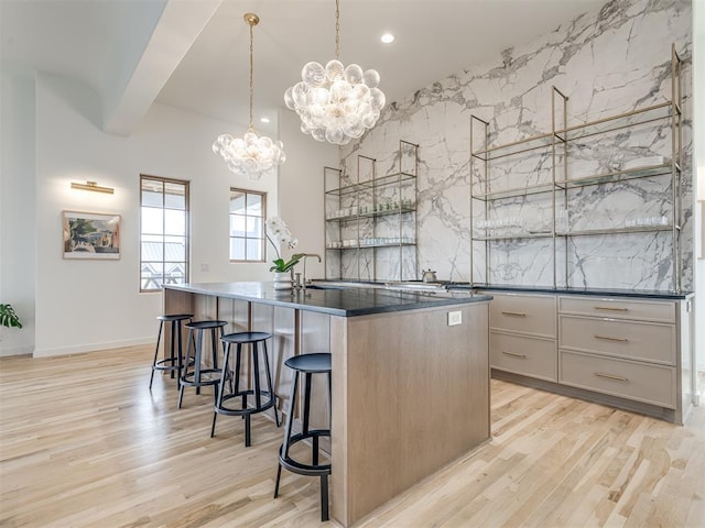 kitchen featuring light hardwood / wood-style flooring, a notable chandelier, pendant lighting, a breakfast bar, and a center island with sink